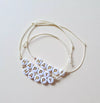 Bracelet perles lettres blanches avec inscription dorée "HAPPY", monté sur un fil ajustable – un bijou fantaisie joyeux et tendance pour enfant ou ado, idéal comme petit cadeau ou accessoire porte-bonheur. Marque Mini Galaxie.
