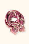 Petit foulard "Manika Bloom Macadamia" signé Apaches Collections. Ce foulard en coton doux arbore un motif floral rose foncé et prune, associé à un imprimé à carreaux beige et rose sur les bordures. Un accessoire de mode chic et tendance, idéal pour sublimer vos tenues avec une touche bohème et raffinée.