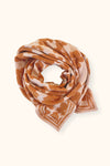 Petit foulard "Manika Flora Bold Orange" de la marque Apaches Collection. Accessoire tendance en tissu léger avec un motif floral vintage dans des tons chauds d'orange et beige. Idéal pour apporter une touche bohème et élégante à votre tenue. Peut être porté autour du cou, dans les cheveux ou en accessoire de sac.