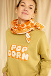 Petit foulard "Manika Flora Bold Orange" de la marque Apaches Collection. Accessoire tendance en tissu léger avec un motif floral vintage dans des tons chauds d'orange et beige. Idéal pour apporter une touche bohème et élégante à votre tenue. Peut être porté autour du cou, dans les cheveux ou en accessoire de sac.