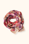 Grand foulard "Latika Joy Macadamia" de la marque Apaches Collections. Accessoire en coton doux avec un imprimé floral aux teintes vives de rouge, violet et orange, sublimé par des bordures beige rayées. Ce foulard polyvalent et tendance peut se porter en bandana, autour du cou ou comme accessoire de cheveux pour un style bohème et élégant.