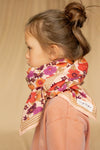 Grand foulard "Latika Joy Macadamia" de la marque Apaches Collections. Accessoire en coton doux avec un imprimé floral aux teintes vives de rouge, violet et orange, sublimé par des bordures beige rayées. Ce foulard polyvalent et tendance peut se porter en bandana, autour du cou ou comme accessoire de cheveux pour un style bohème et élégant.