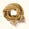 Petit foulard "Manika Mosaic Tobacco" de la marque Apaches Collections. Accessoire en coton doux avec un motif mosaïque géométrique et des bordures florales dans des tons tabac et beige. Idéal pour sublimer une tenue avec une touche bohème et chic, ce foulard peut se porter autour du cou, en bandeau ou en accessoire de sac.
