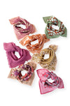 Petit foulard "Manika Bloom Macadamia" signé Apaches Collections. Ce foulard en coton doux arbore un motif floral rose foncé et prune, associé à un imprimé à carreaux beige et rose sur les bordures. Un accessoire de mode chic et tendance, idéal pour sublimer vos tenues avec une touche bohème et raffinée.