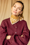 Petit foulard "Manika Mosaic Tobacco" de la marque Apaches Collections. Accessoire en coton doux avec un motif mosaïque géométrique et des bordures florales dans des tons tabac et beige. Idéal pour sublimer une tenue avec une touche bohème et chic, ce foulard peut se porter autour du cou, en bandeau ou en accessoire de sac.